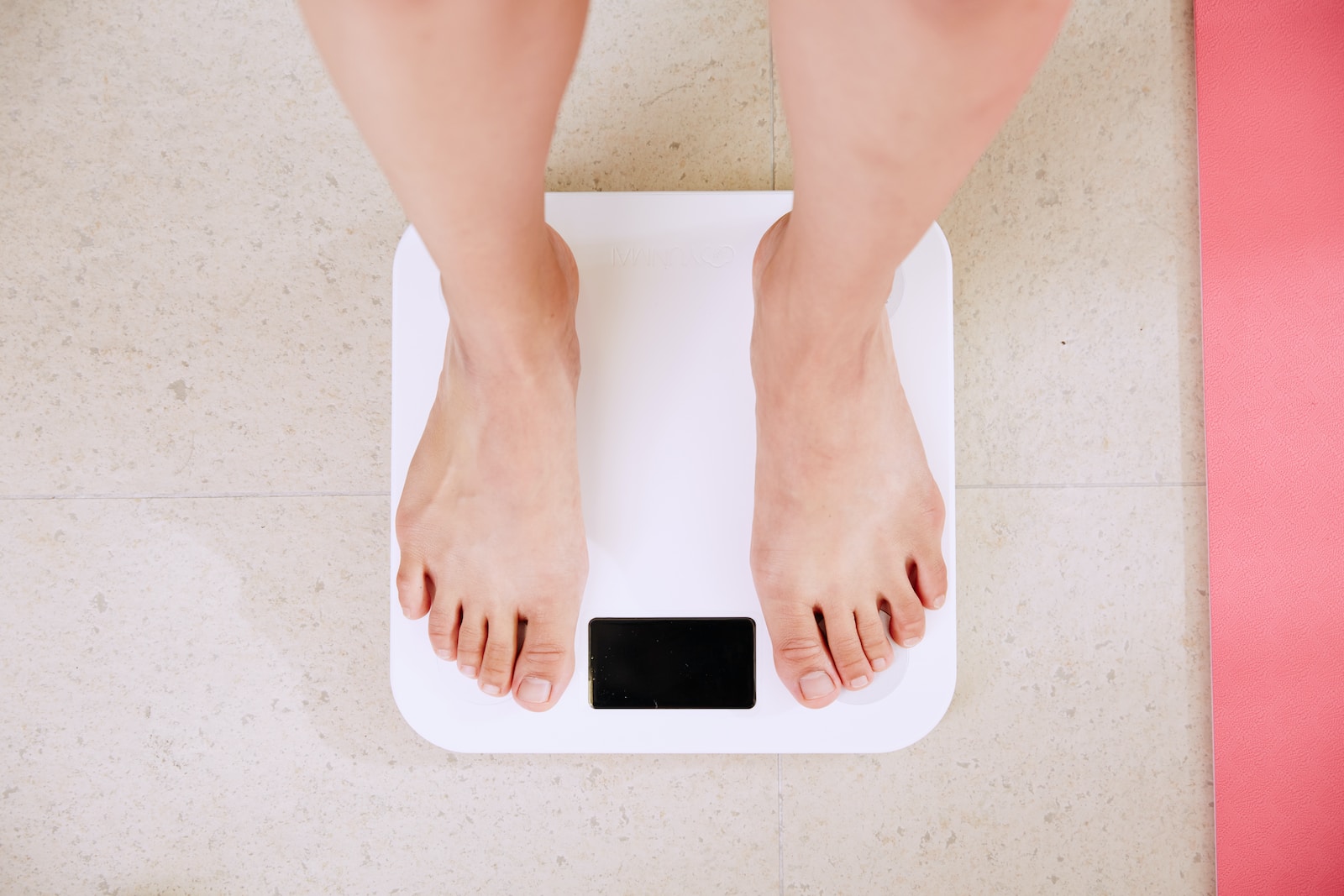 person monitoring weight loss on bathroom scale